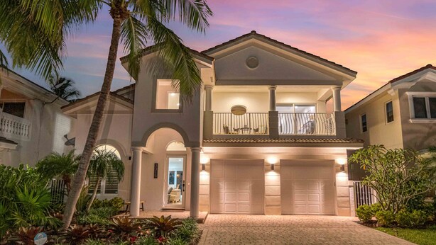 A two-story house with a balcony, a garage, and a well-maintained garden.