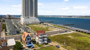 A coastal area with a tall hotel, a historic house, and a bridge over water.