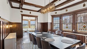 A dining area with a long table, chairs, and a chandelier.