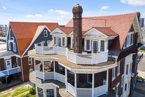 A multi-story house with a prominent brick chimney, multiple balconies, and a wooden deck.