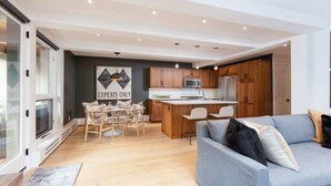 Une cuisine moderne avec des meubles en bois, un îlot central et un coin repas comprenant une table et des chaises.