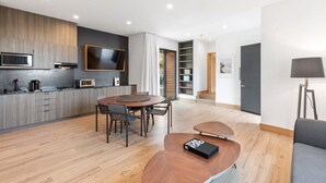A modern kitchen with a dining area, a flat-screen TV, and a bookshelf.