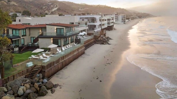 A coastal hotel with a beach view, outdoor seating, and a wooden deck.