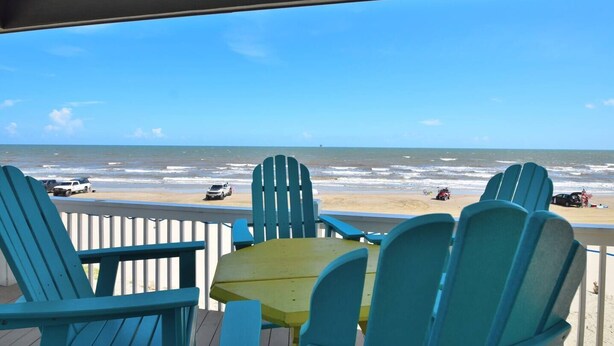 A beach view from a covered deck with blue Adirondack chairs and a small table. - Shore is Fine - Beachfront, AwesomeViews (Port Bolivar)