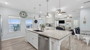 A modern kitchen with a central island, white cabinetry, and pendant lighting. - Shore is Fine - Beachfront, AwesomeViews (Port Bolivar)