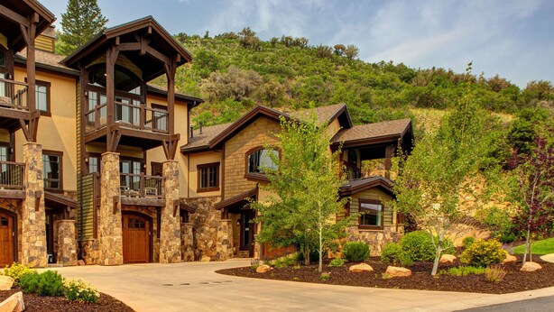 A multi-story house with stone and wood exterior, multiple balconies, and a landscaped driveway. - Experience comfort in Park City Fairway Springs 4221, a 3BR townhome near Canyons Village. (Park City)