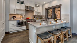 A modern kitchen with white cabinetry, a central island with stools, and a window with a view. - Experience comfort in Park City Fairway Springs 4221, a 3BR townhome near Canyons Village. (Park City)