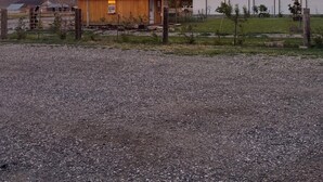 A gravel driveway leading to a wooden building with a metal roof, adjacent to a white building with a metal roof. - Hales Hideaway by the City of Rocks (Oakley)
