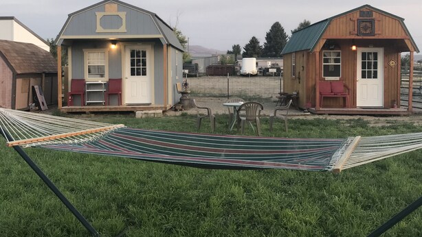 Two small wooden cabins with attached porches, a hammock, and a fenced area with a table and chairs. - Hales Hideaway by the City of Rocks (Oakley)