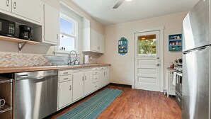 Una cocina moderna con gabinetes blancos, electrodomésticos de acero inoxidable y piso de madera.