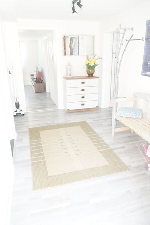 A bright, modern bathroom with a wooden bench, a mirror, and a shower area.