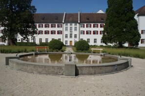 A large building with a symmetrical facade, a central courtyard with a fountain, and a well-maintained garden.