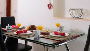 Een eetgedeelte met een glazen tafel, zwarte stoelen en hartvormige decoraties aan de muur.
