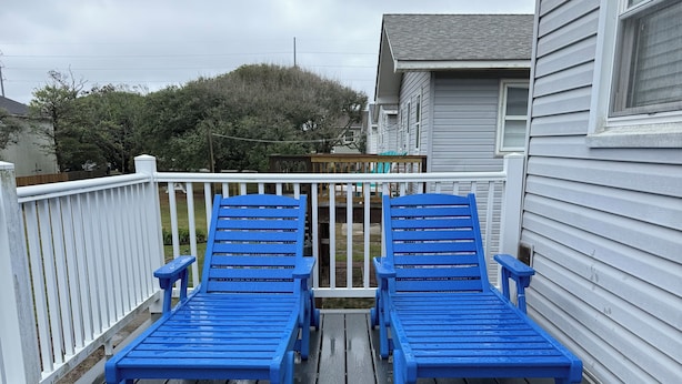 Una terraza con dos sillones azules y una barandilla blanca.