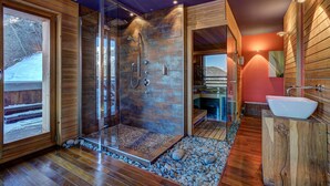A modern bathroom with a glass-enclosed shower, wooden walls, a white sink, and a pebble-tiled floor. - Chalet Auriane - Five Bedroom Chalet, Sleeps 12 (Riddes)