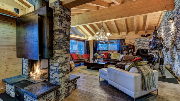 A cozy living room with a stone fireplace, wooden beams, and a comfortable seating area. - Chalet Auriane - Five Bedroom Chalet, Sleeps 12 (Riddes)