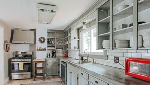 A kitchen with a stainless steel stove, a dishwasher, and a red retro-style microwave.