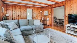 A cozy living room with a sectional sofa, a coffee table, and wooden walls.