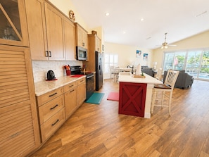 A modern kitchen with wooden cabinets, a microwave, and a refrigerator. - Lovely Pool Home With Spa & Games Room Close to WDW (Clermont)