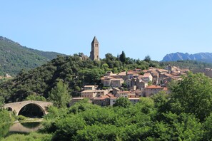 A historic town with a prominent tower and a stone bridge over a river.