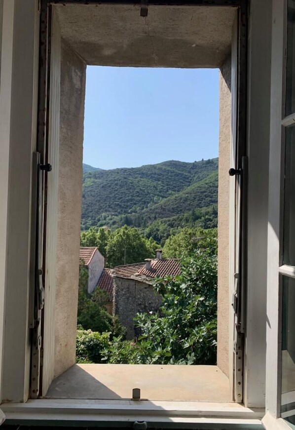 Une fenêtre donnant sur un paysage montagneux, avec un ciel dégagé.