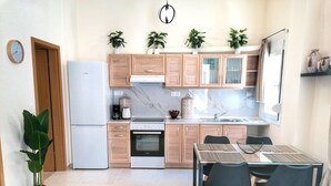 A modern kitchen with wooden cabinets, a built-in oven, and a dining area with a table and chairs.