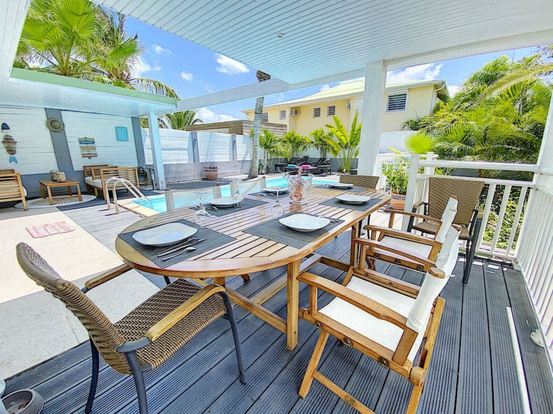 Un espace extérieur abrité où l’on peut prendre ses repas, avec une piscine en arrière-plan.