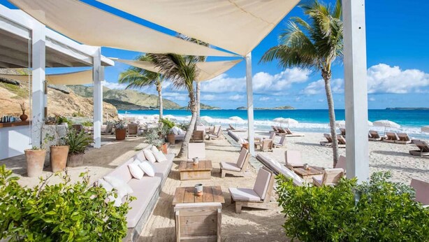 A beachside lounge with outdoor seating, palm trees, and a view of the ocean. - Villa Zandoli – Private Pool Just Steps from Orient Bay Beach, 3 bedrooms (Orient Bay)
