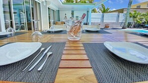 An outdoor dining area with a table set for two, a glass pitcher, and a bottle of champagne. - Villa Zandoli – Private Pool Just Steps from Orient Bay Beach, 3 bedrooms (Orient Bay)