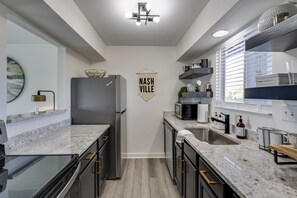 A modern kitchen with granite countertops, stainless steel appliances, and a 'Nashville' sign on the wall.