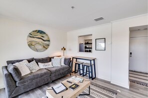 A modern living room with a grey sofa, a coffee table, and a painting on the wall.