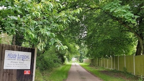 Ein Privatweg führt zu den Hillside Bungalows, umgeben von üppigem Grün und einem Holzzaun.