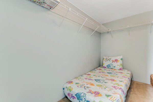 A bedroom with a bed, a white ceiling fan, and a wall-mounted shelf. - Family-friendly ocean view on no-drive Ormond with heated beachfront pool and garage (Ormond Beach)