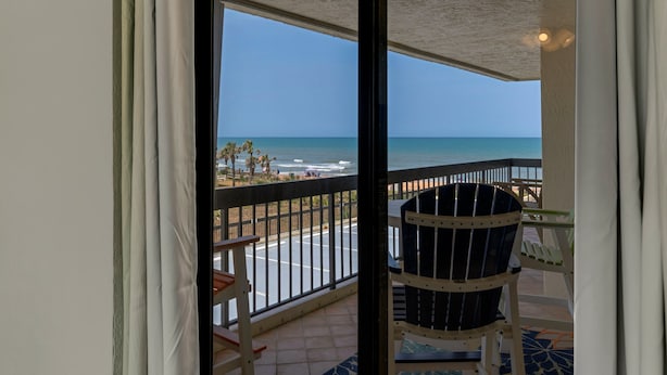 A balcony with a view of the beach and ocean.