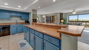 A modern kitchen with blue cabinets, a wooden countertop, and a built-in dishwasher.