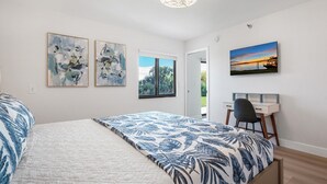 A bedroom with a bed, a desk, and two abstract paintings.