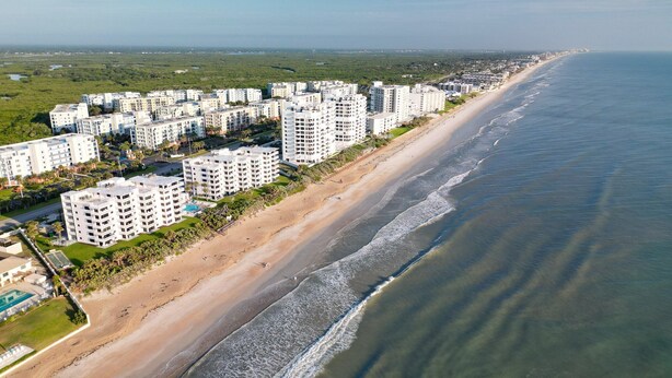 A coastal residential area with high-rise buildings, a sandy beach, and a clear view of the ocean.