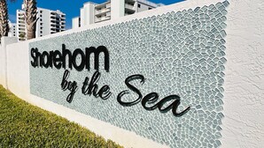 A sign with the text "Shoreham by the Sea" on a textured wall.