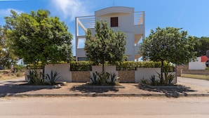 Un edificio moderno con fachada curva, rodeado de jardines cuidados y un camino pavimentado.