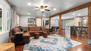 A spacious living room with a brown leather sectional sofa, a large patterned rug, and wooden flooring. - Family Fun Hocking Hills Retreat, 2 Decks, Game Rm (Logan)