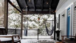 A covered porch with a hammock, a railing, and a view of a snow-covered landscape. - Family Fun Hocking Hills Retreat, 2 Decks, Game Rm (Logan)