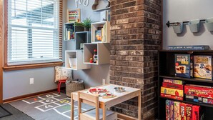 A children's play area with a window, shelves with toys, and a brick wall. - Family Fun Hocking Hills Retreat, 2 Decks, Game Rm (Logan)