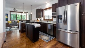 Une cuisine moderne avec des meubles en bois foncé, des appareils électroménagers en acier inoxydable et un îlot central.