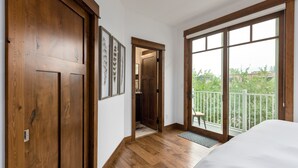 Une chambre dotée d’une grande fenêtre, d’un plancher en bois et d’un balcon avec une balustrade.