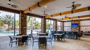 A restaurant with outdoor seating, a pool, and a waterfall. - Crisp & Pristine Pool & Spa & Game Room Home! Solterra Resort! (Davenport)