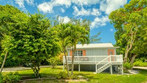 A house with a porch, a staircase, and a lawn. - Baywatch Cabin- Boat Dock on the Channel (Captiva)