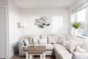 A modern living room with a sectional sofa, a small wooden coffee table, and a decorative wall mirror.