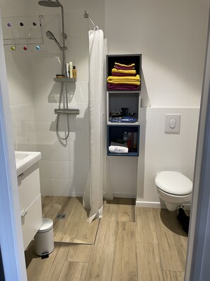 Une salle de bain moderne équipée d’une douche, de toilettes et d’étagères de rangement.