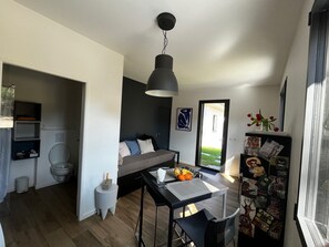 Un espace de vie moderne comprenant un coin repas, un canapé et une petite table sur laquelle se trouve un saladier rempli de fruits.