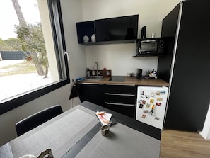A compact kitchen with a window, a refrigerator, a microwave, and a small countertop.